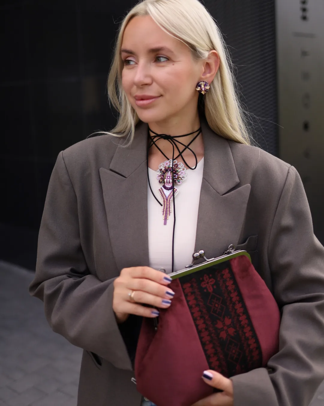 Жінка в сірому пальті з бордовим саквояжем